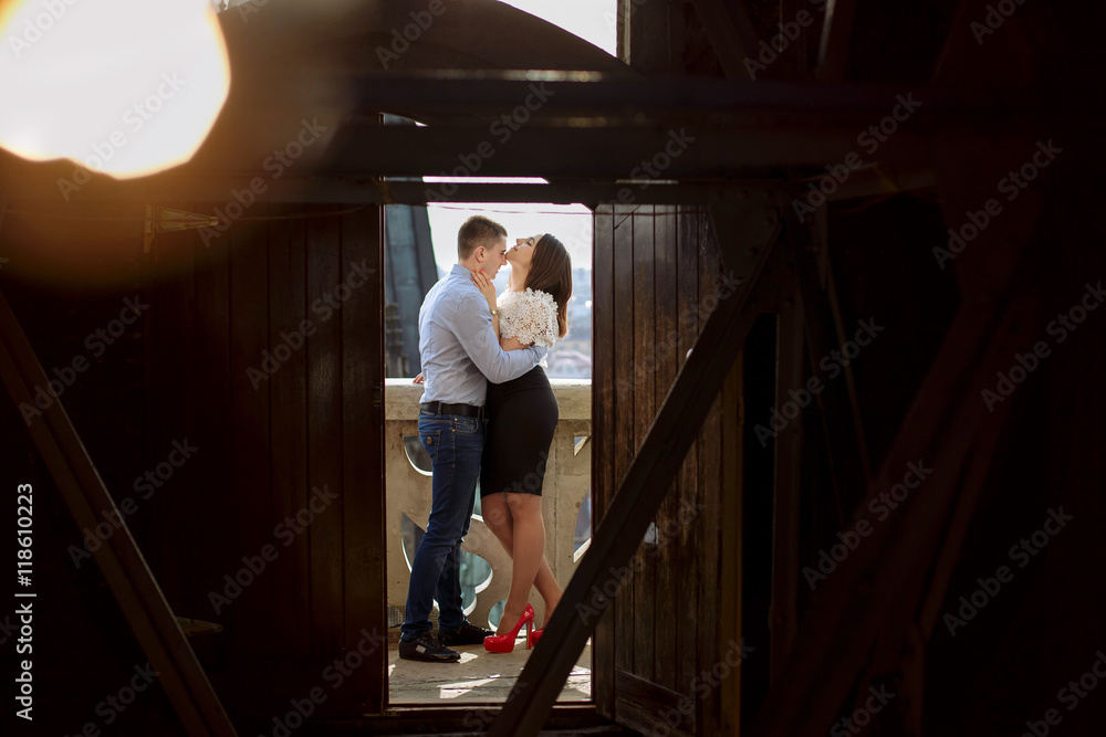Fototapeta premium Look through the wooden door at a couple kissing on the roof