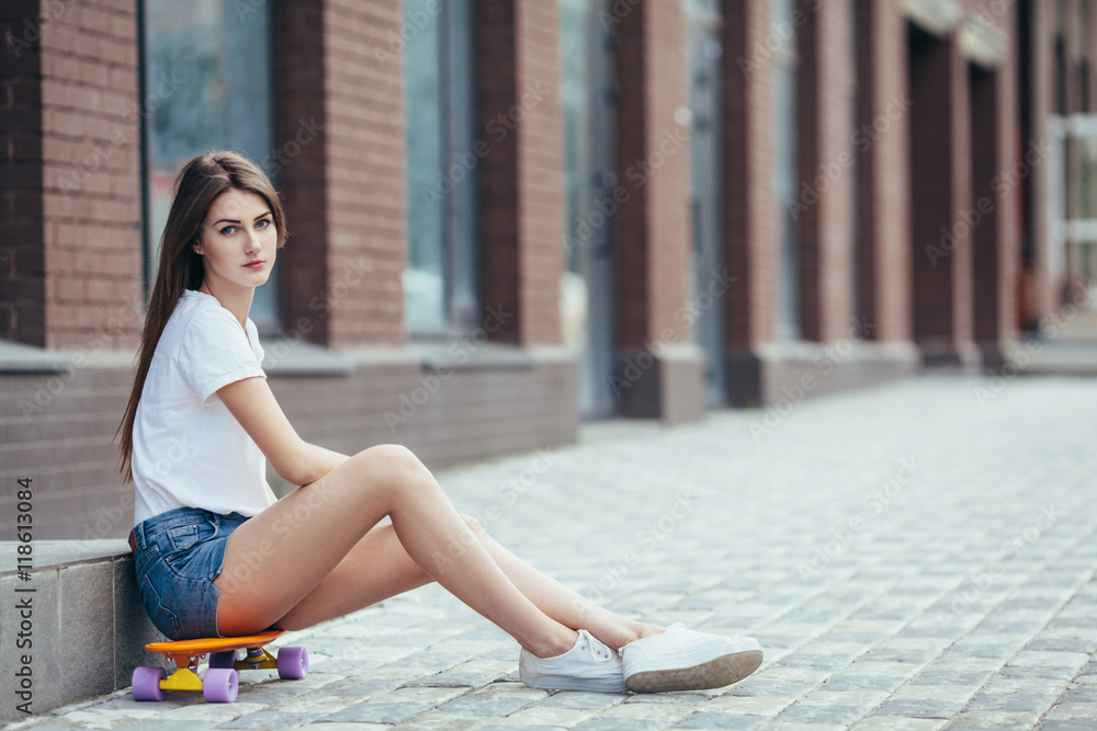 Sport fashion brunette girl in denim shorts, posing in summer wi