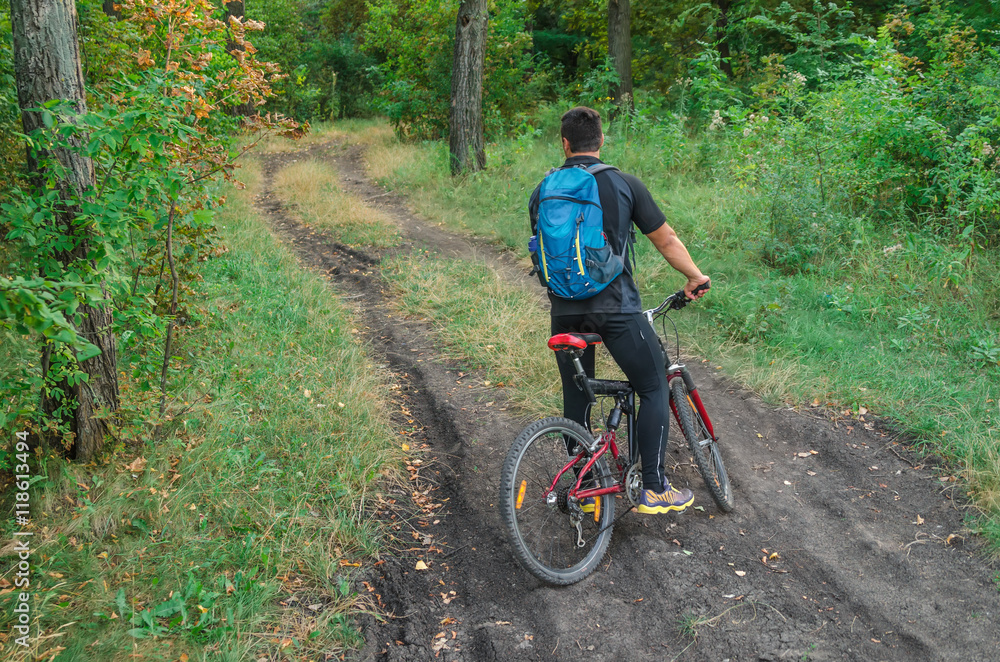 Mountainbiker riding on bicycle in summer park at sunny day.