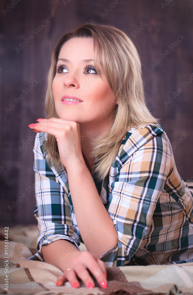 Fototapeta premium Portrait of a young attractive woman lying on plaid blanket, close-up