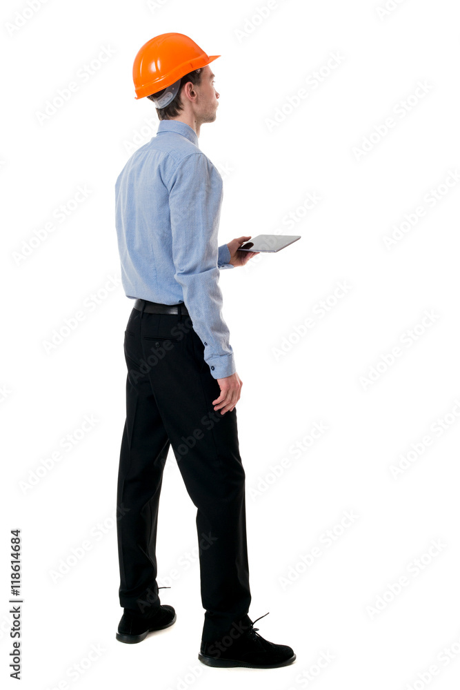 Backview of business man in construction helmet stands and enjoys tablet or using a mobile phone. Standing young guy. Rear view people collection. backside view of person. Isolated over white Backview of business man in construction helmet stands and enjoys tablet or using a mobile phone. Standing young guy. Rear view people collection. backside view of person. Isolated over white