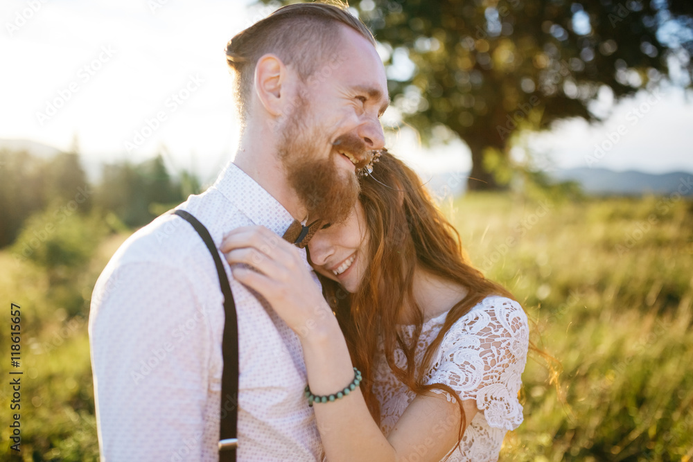 Fototapeta premium Bearded groom laughs while hugging his beautiful bride