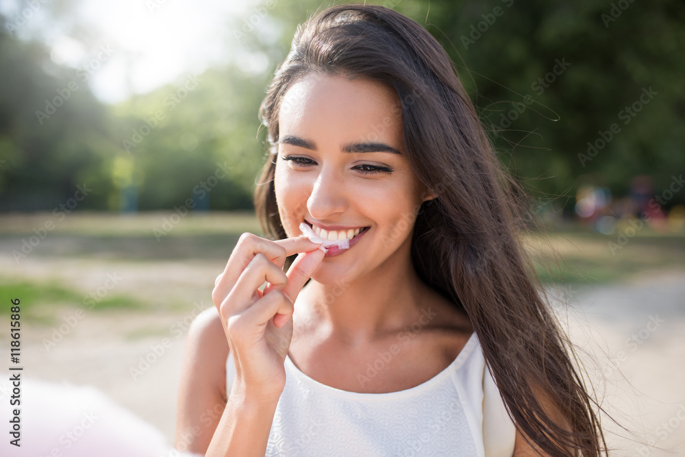 Amazing and beautiful close-up portrait of young happy woman, smile and eat cotton candy on nature background. Inspiration Amazing and beautiful close-up portrait of young happy woman, smile and eat cotton candy on nature background. Inspiration