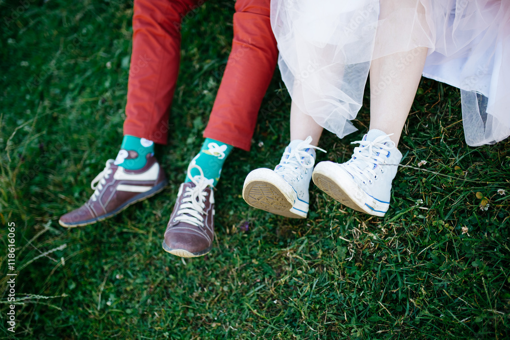 Newlyweds legs in keds and funny socks lie on the green lawn Newlyweds legs in keds and funny socks lie on the green lawn