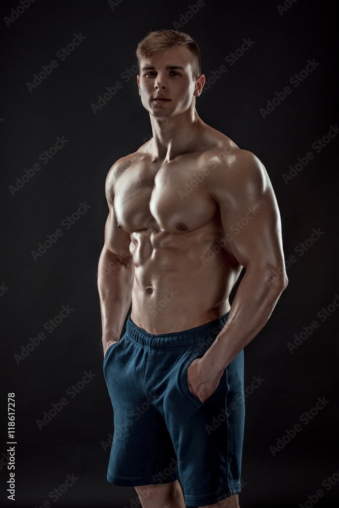 Fototapeta premium Muscular bodybuilder guy doing posing over black background