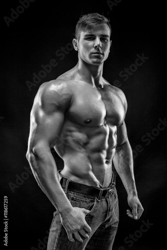 Muscular bodybuilder guy doing posing over black background