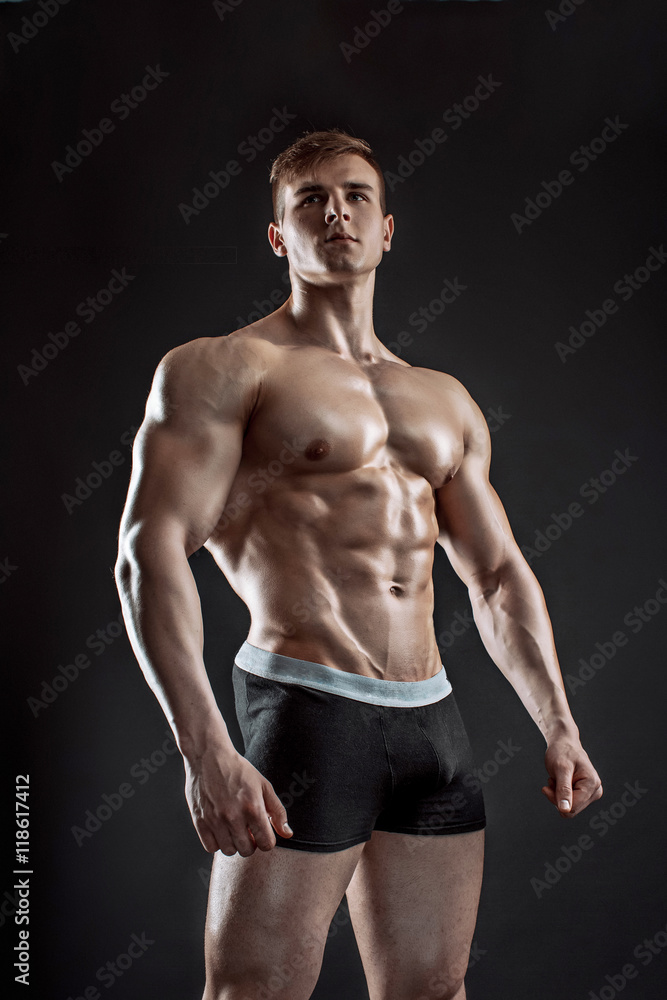 Fototapeta premium Muscular bodybuilder guy doing posing over black background