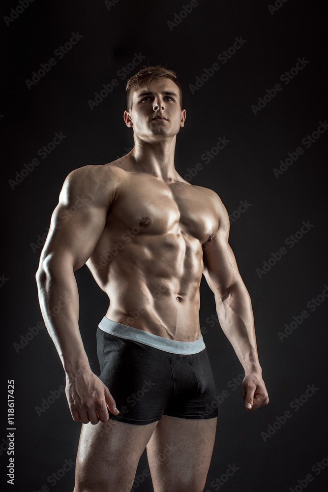 Muscular bodybuilder guy doing posing over black background Muscular bodybuilder guy doing posing over black background