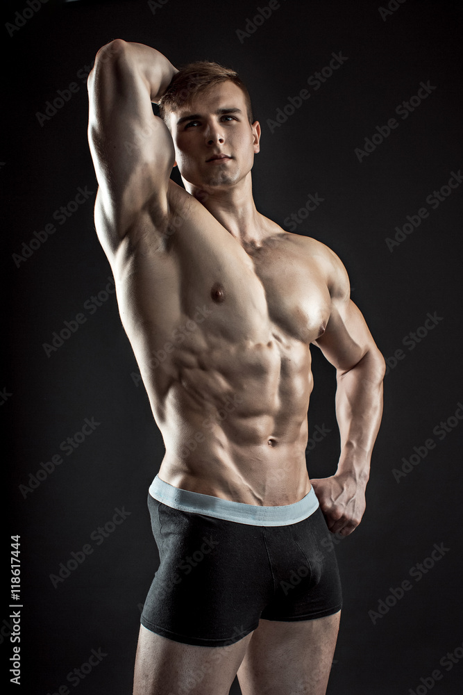 Muscular bodybuilder guy doing posing over black background Muscular bodybuilder guy doing posing over black background
