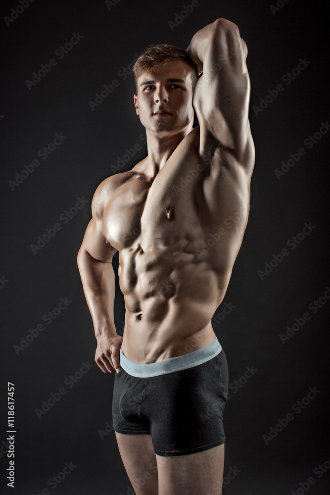 Muscular bodybuilder guy doing posing over black background