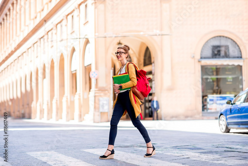 Young female student crossing the street on the way to university in Bologna city in Italy