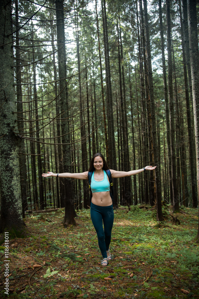 Young beautiful girl tourist with a Hiking backpack and a sports figure walking in the woods Young beautiful girl tourist with a Hiking backpack and a sports figure walking in the woods