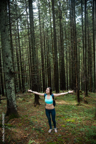 Young beautiful girl tourist with a Hiking backpack and a sports figure walking in the woods