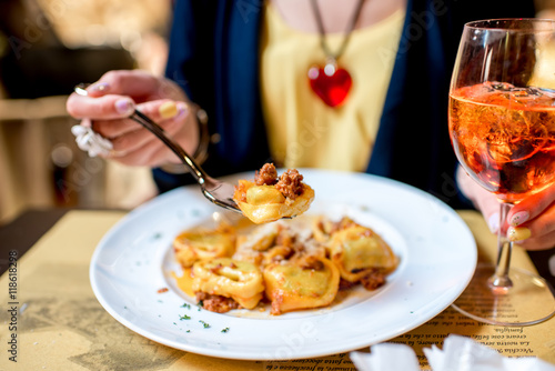 Eating a dish with traditional ring-shaped pasta tortellini and spritz aperol drink