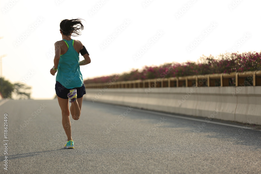 young woman runner running on city bridge road