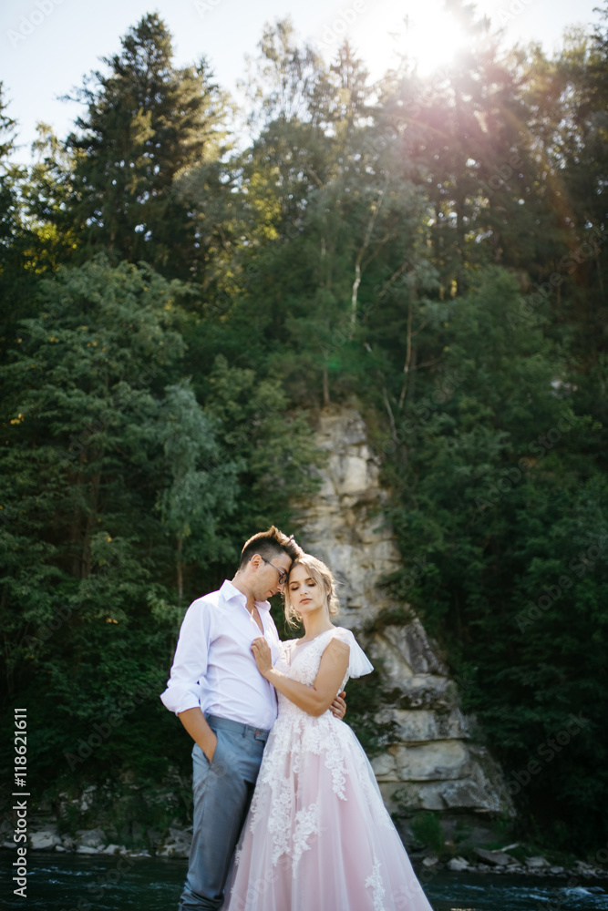 Bride and groom daydream in the rays of sun under the mountain r Bride and groom daydream in the rays of sun under the mountain r