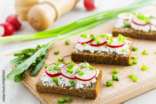 Open sandwiches with soft cream cheese and fresh radish. Summer food on table.