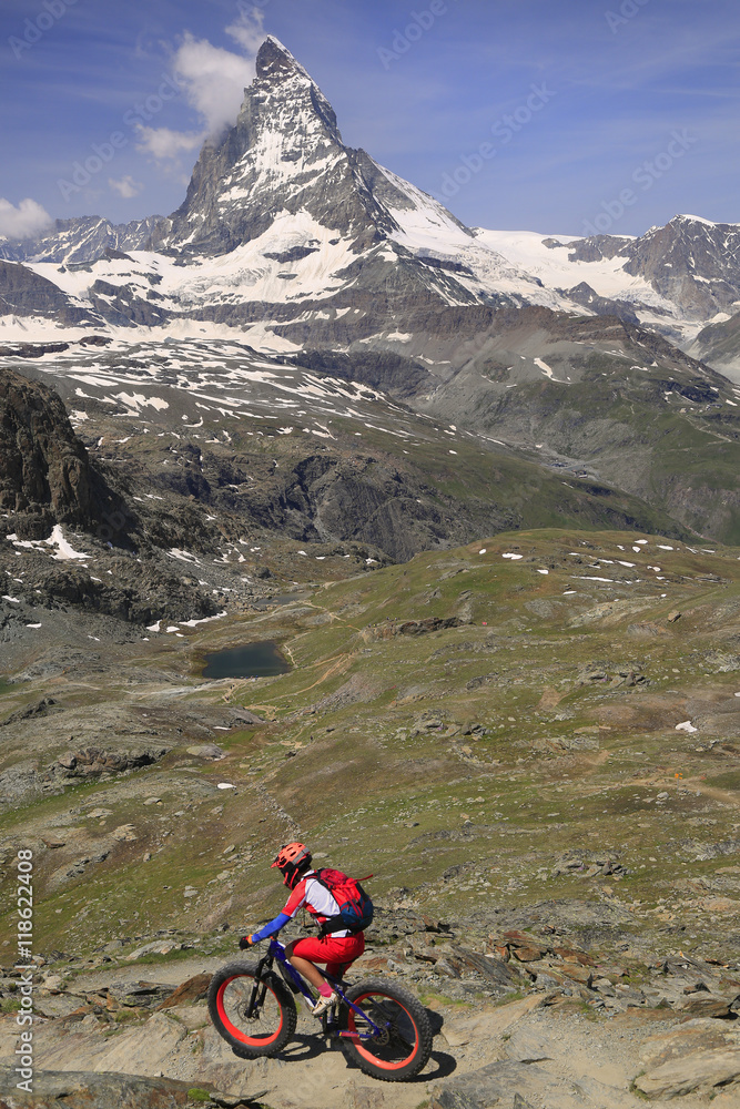 Fototapeta premium View of Matterhorn and cyclist enjoying the challenge on mountain trails.