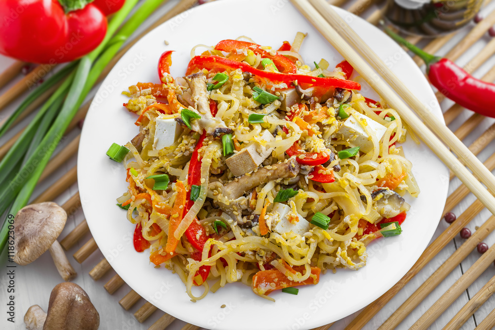 Stirred rice noodles with vegetables, tofu and shiitake mushroom. Traditional Asian food. Top view, close-up. Stirred rice noodles with vegetables, tofu and shiitake mushroom. Traditional Asian food. Top view, close-up.