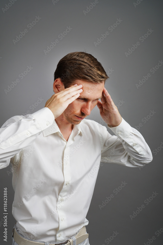 Young man in white shirt thinking or experiencing headaches. Young man in white shirt thinking or experiencing headaches.