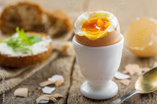 Perfect soft boiled egg and open bread sandwich with butter and dill on a table. Traditional food for healthy breakfast.