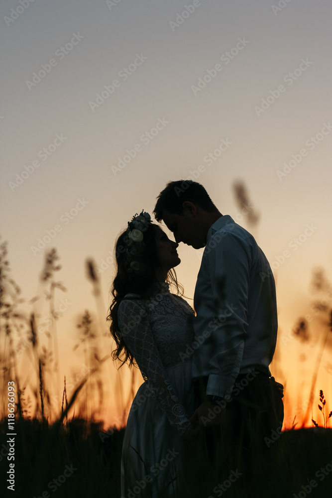 Silhouettes of stunning couple standing on the field in evening