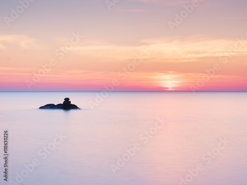 Obraz na plátně Romantic sea. Boulders stick out from smooth sea.