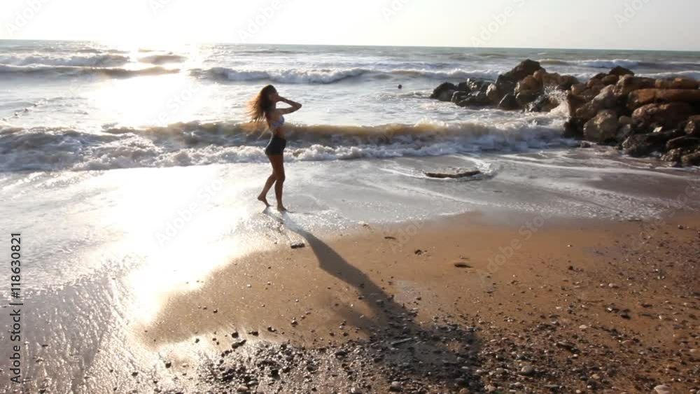 young brunette woman walking along the beach and is photographed at sea young brunette woman walking along the beach and is photographed at sea