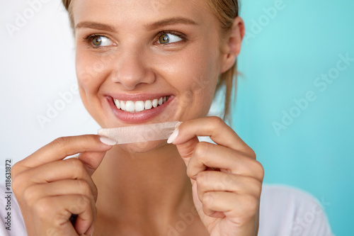 Fototapeta Naklejka Na Ścianę i Meble -  Woman With Healthy White Teeth Using Teeth Whitening Strip. High Resolution Image