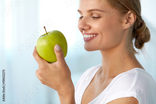 Beautiful Smiling Woman With White Teeth Eating Green Apple. High Resolution Image