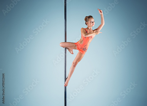 The strong and graceful young girl performing acrobatic exercises on pylon