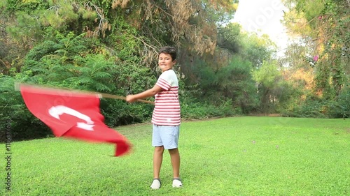 Portrait of a young boy holding and waving the flag of Turkey at the park