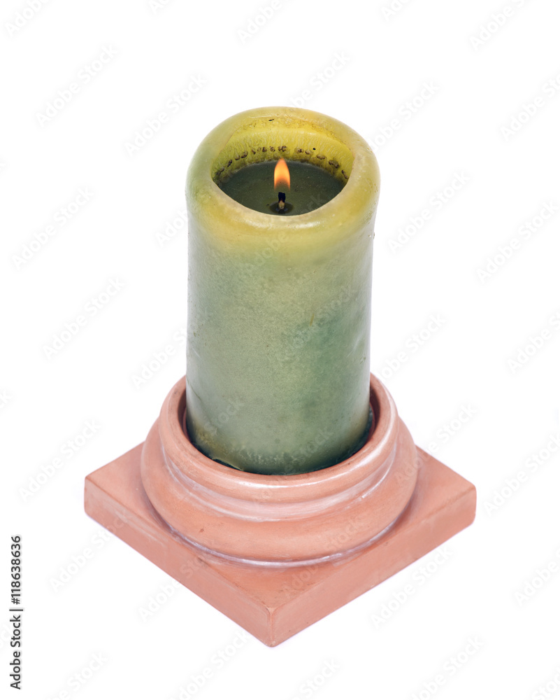 Burning green candle in clay holder separated on white background Burning green candle in clay holder separated on white background