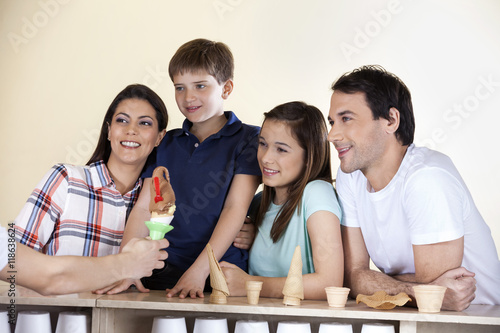 Family Looking At Waiter Giving Ice Cream At Counter