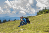 Male Hiker sitting, looking through a binocular on the Rax mountain Austria