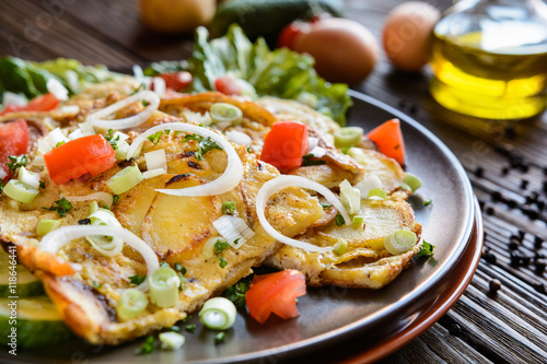 Typical Spanish tortilla - omelet with potatoes and onion with vegetable garnish