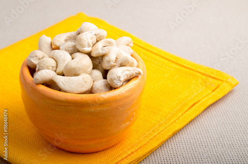 Raw cashew nuts in a small orange cup closeup photo