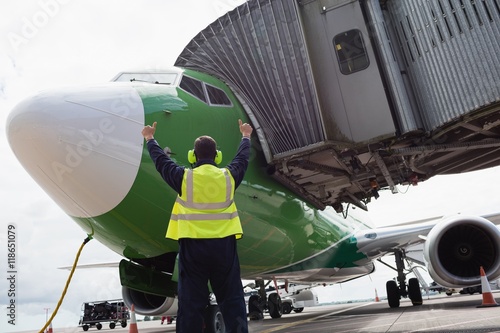 Rear view of airport ground crew worker directing airplane photo