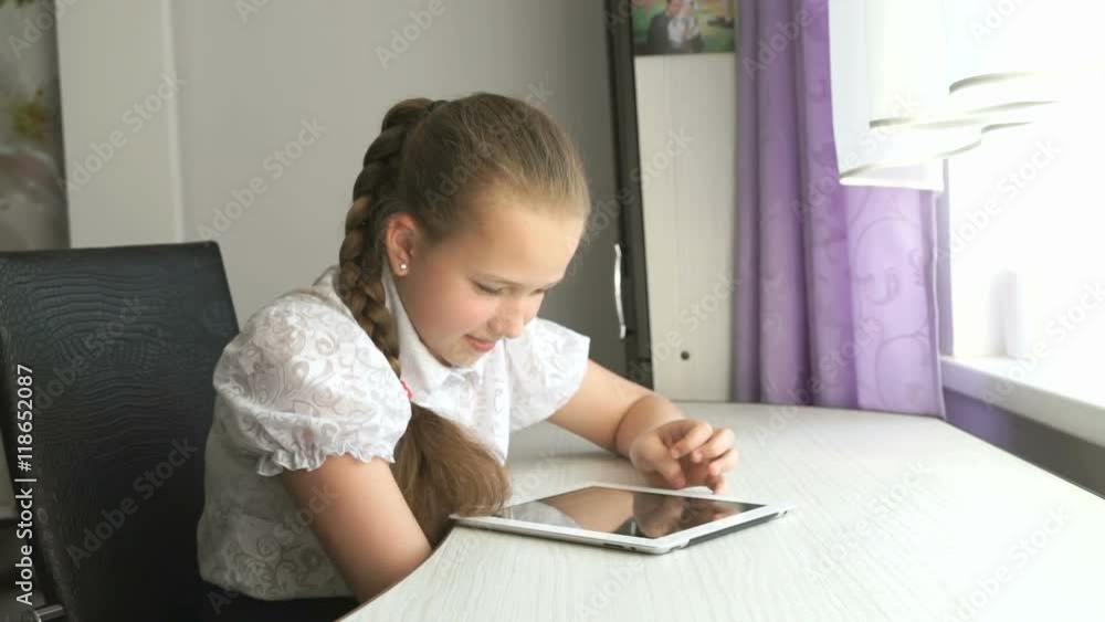 Schoolgirl uses a digital tablet computer at home Schoolgirl uses a digital tablet computer at home