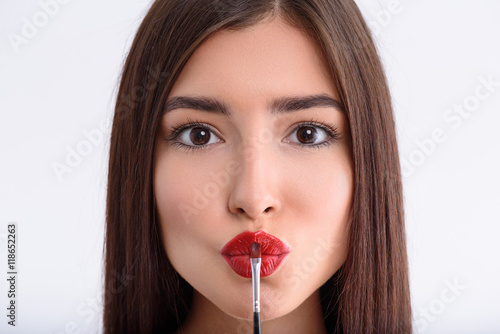 Cheerful woman applying paint on lips