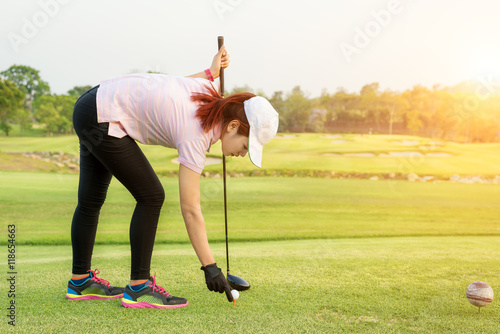 Asian woman putting golf ball on tee to already to play golf.