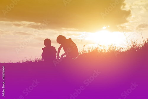 silhouette Children playing with sand. The evening sunset. © stcom