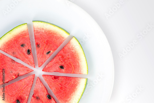 Watermelon slices arranged on a white plate on a white background with copy space