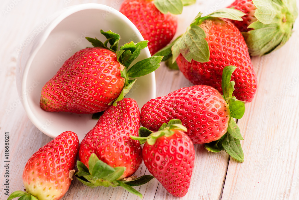 Fresh strawberries in white ceramic bowl on wood table Fresh strawberries in white ceramic bowl on wood table