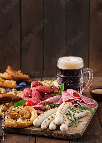 Glass of beer, pretzels and various sausages on wooden background. Oktoberfest.