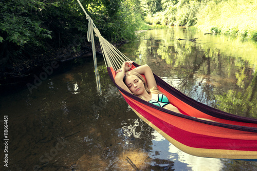 girl in a bathing suit lying in a hammock over the water