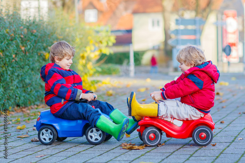 Two little kids boys playing with toy cars, outdoors