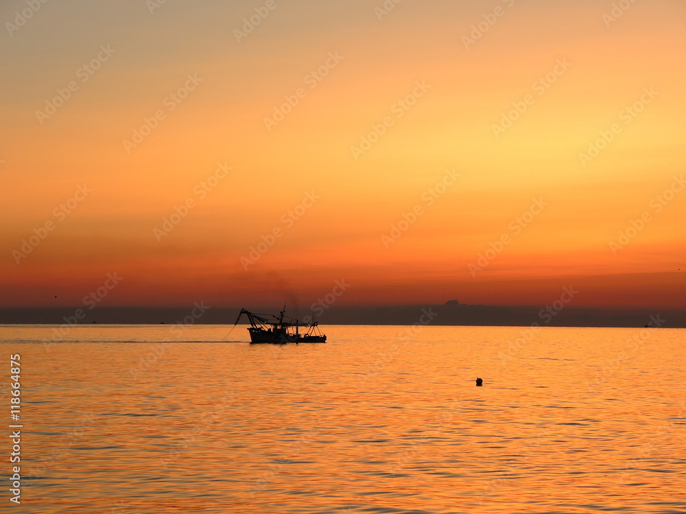 Fishing boats pull their nets at the sunrise. Adriatic cost. Emilia Romagna. Italy.