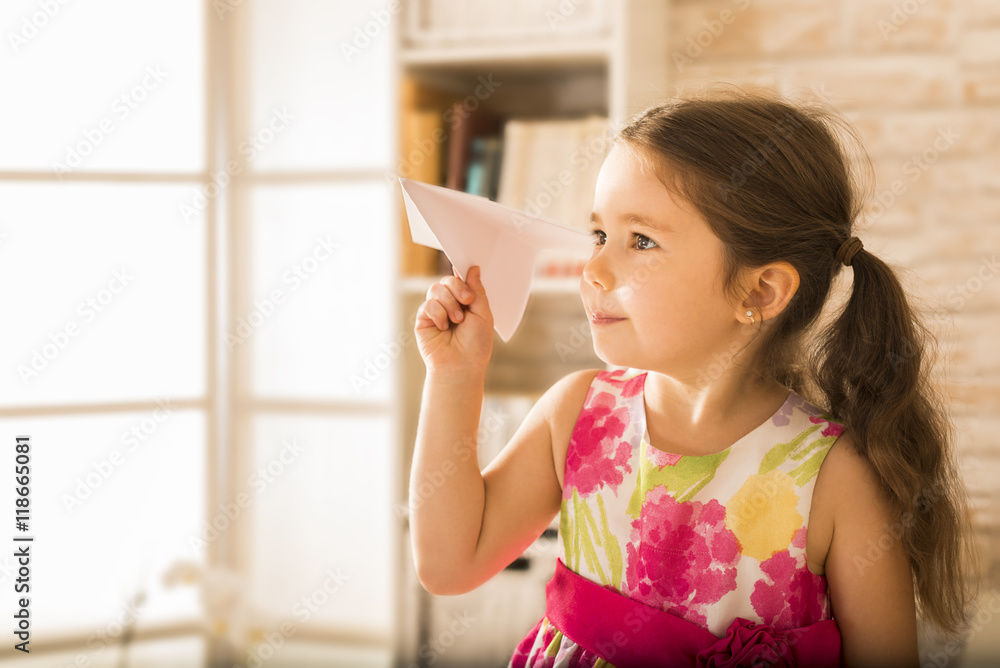 Children's play concept. Adorable little girl playing with origami paper airplane Children's play concept. Adorable little girl playing with origami paper airplane
