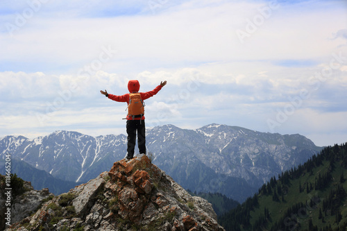 cheering woman hiker open arms on mountain peak © lzf